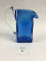 Front view of cobalt blue glass jug with a clear handle, showing the rectangular body and shaped spout.