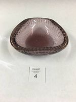 Front angled view of a shallow, lavender triangular-shaped glass bowl showing the presence of controlled air bubbles embedded in the glass.