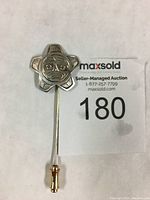 Full view of the Richard E. Baker sterling silver stick pin showing the entire length with attached clasp and engraved sun design head.