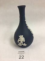 Front view showing cherub with a basket and floral relief on dark blue vase.