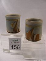 Photo showing front view of two yunomi tea cups with earthy glaze patterns and rounded rims.