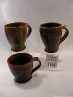 Three ceramic mugs in different poses showing their glaze and shape