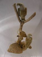 Front view of the carved stone eagle statue showing three eagles perched on a branch set on a textured base.