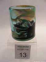 Front view of the Lumel Glass Studio art glass drinking glass showing the colorful swirl pattern and the thick glass base.