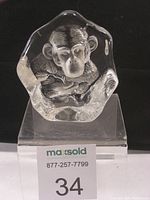 Front view of glass chimpanzee sculpture showing detailed face and ears inside clear glass