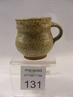Front side view of Heinz Laffin small coffee mug showing bulbous shape and handle with speckled beige glaze.