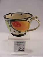 Side view of ceramic mug showing orange and yellow leaf motifs, black polka dots, and cream-colored handle with decorative top connection.