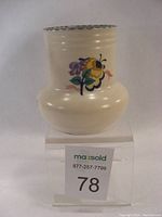 Front and side view of bulb vase showing hand-painted floral design, cream glazed finish, and scalloped green-blue edge rim.