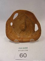 Front view of small carved cedar bowl showing organic rounded triangular shape and two carved freeform cut-out handles