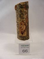 Front view of the birch branch with one carved face visible, showing detailed facial features carved into the bark.