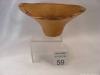 Front view of a turned wooden bowl made from alder wood with natural bark edge, sitting on a clear display stand.