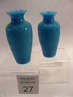 Two vintage blue art glass vases shown front view with etched floral motifs.