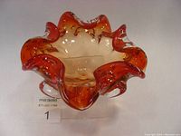 Front angled view of vintage Murano amberina art glass bowl showing ruffled red-tinted edges and clear body with bubbles