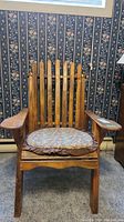 Front view of the wooden Adirondack chair with removable floral seat cushion placed on a carpeted floor against floral wallpaper.