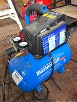 Full view of blue Mastercraft air compressor with pressure gauges and power switch on black top unit, showing build and condition.