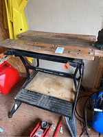 Full view of Black & Decker Workmate 400 wooden top workbench with metal frame and base shelf, showing overall wear and setup in shed.