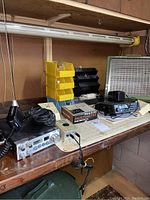 Shelf with two Uniden CB radios, digital multimeter, circuit tracer, power adapter, and storage trays.