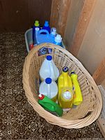 Photo showing large woven basket filled with various laundry detergent bottles and jugs in multiple colors placed inside the 1966 vintage baby’s bath tub.