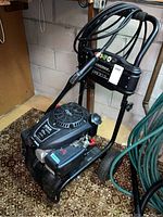 Full-view of pressure washer on basement floor showing frame, engine, wheels and hose