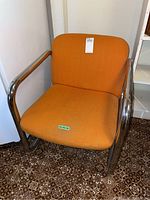 Front and side views of a retro arm chair with tubular chrome metal frame and orange upholstery, showing condition and design details.