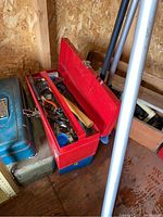 Red metal toolbox open showing assorted hand tools including hammer, pliers, wrenches, and screwdriver
