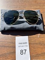 Front view of Breed aviator sunglasses resting on soft pouch on wooden surface