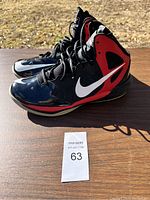 Side view of pair of black and red Nike basketball shoes with white swoosh logo, size 12, showing overall condition and style