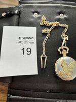 Front view of silver pocket watch with embossed eagle and attached chain.