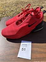 Pair of red Nike Air sneakers shown from side angle, highlighting mesh upper and black swoosh logo.