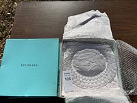 Original Tiffany & Co. blue box next to the glass tray wrapped in protective packaging.