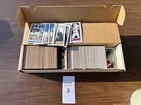 Top-down view of box filled with vintage baseball cards in different sleeves and loose, showing quantity and packaging