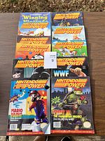 All magazines laid out on a wooden surface, showing colorful vintage Nintendo Power magazine covers, total of 10 magazines.