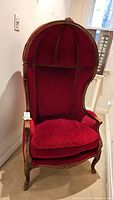 Front view of red velvet balloon back armchair with carved wood frame