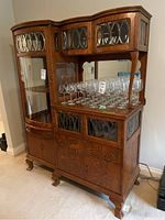 Front view of oak china cabinet showing left curved glass door and right mirrored back shelf with glassware