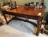 Front-side angle of entire desk showing inlaid top, drawer fronts, carved legs