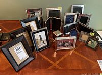 Photo of multiple assorted photo frames of different materials and sizes on a wooden table.