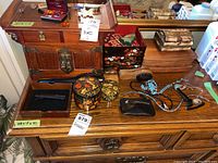 Wide view of wooden jewelry boxes and trays on wood dresser with various jewelry and accessories scattered