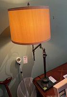Full view of desk lamp showing fabric shade and metal base with articulated arm.