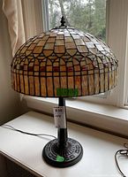 Full view of lamp showing stained glass shade and metal floral motif base