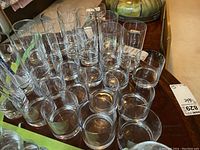 Multiple clear Pasabahce highball and tumbler glasses arranged on a wooden table with price tags visible.