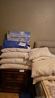 Pillows stacked with new Sunset Oreiller Heavenly Touch pillow box visible behind