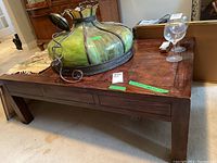 View of the wood coffee table top showing burled wood inlays and some finish wear. Glassware and decor items visible but not included.