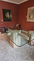 Frontal angle view of rectangular glass top table with travertine marble base in room setting