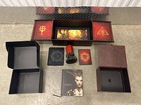Full Diablo 4 collector's box opened displaying inner compartments and all contents spread on floor.