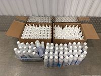 Two open cardboard boxes and a plastic bin filled with many white plastic bottles of GermEze hand sanitizer with white caps.