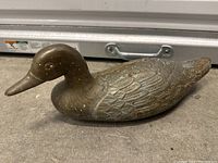 Metal duck figurine showing detailed engraving on the body and overall shape
