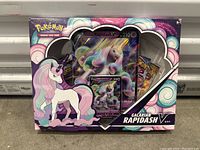 Front view of sealed Pokemon Galarian Rapidash V trading card box showing the included holographic card and booster packs clearly visible through the packaging window.