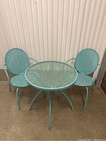 Full view of the bistro set including two chairs and a round glass tabletop table.