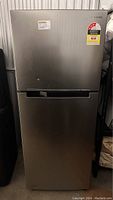 Front view of Samsung refrigerator, stainless steel with handle, minor front marks visible.
