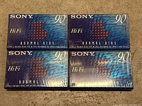 Four sealed Sony Hi Fi Normal Bias 90-minute audio cassette tapes in original packaging arranged side by side on a carpeted surface.